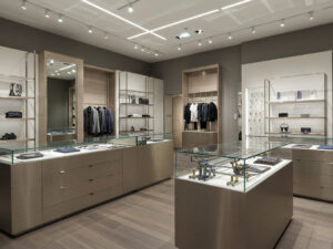 A beautifully lit, high-end retail store interior, fully completed and visually clean. Focus on elegant display fixtures—counters, wall units, and shelving—that appear seamless and minimalist. Subtly integrated into the image: a semi-transparent overlay or x-ray-style cutaway on one or two display fixtures, revealing internal metal supports, wooden frames, and precise joinery without breaking the aesthetic flow. The store features refined materials like brushed metal, glass, and wood, with soft ambient lighting and premium product displays. The image should balance surface beauty with an intelligent hint at the hidden engineering within.