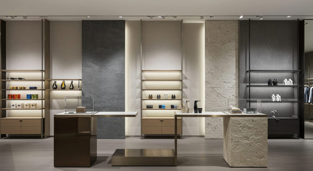 A high-end retail store interior showcasing a variety of display fixtures. The image should emphasize the contrast between different materials—such as glossy metal, natural wood, frosted glass, and textured stone—used in shelving, product stands, and backdrops. Lighting should highlight how these materials guide customer attention across the display area. The atmosphere should be modern and elegant, reflecting a premium shopping experience.